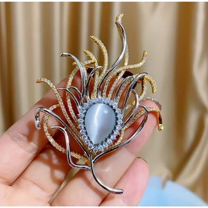 Elegant peacock feather brooch with opal stone and colorful zircons in a handheld view