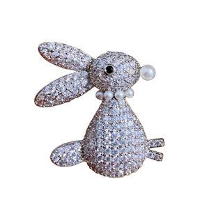 Exquisite gold rabbit brooch with white zircons and pearl details on white background