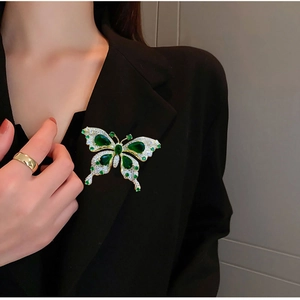 Gros plan sur la broche papillon émeraude sertie de cristaux sur un blazer noir