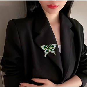 Broche papillon luxueuse avec pierres vert émeraude et cristaux sur revers noir