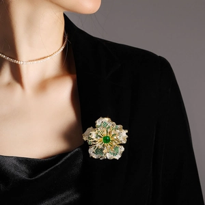 Exquisite gold floral brooch with green and white crystals on a black suit jacket