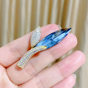 Eleganter Blatt-Brosche in Gold mit blauem Kristall und funkelnden Zirkonia-Details