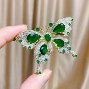 Gros plan d'une broche papillon avec pierres vert émeraude et pavé de zircones cubiques