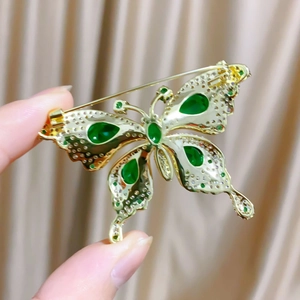 Détail d'une broche papillon émeraude avec dorure et cristaux étincelants