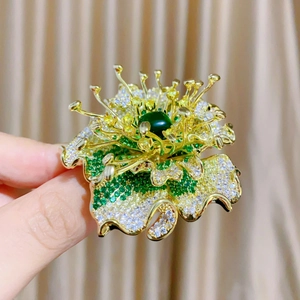 Macro shot of floral brooch detailing zircon petals and emerald green center