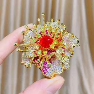 Macro detail of luxury flower brooch with red zircon center and multicolor pavé petals