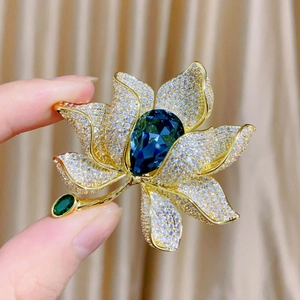 Detailansicht einer luxuriösen Lotus-Brosche mit blauem Kristall und vergoldeten Blüten