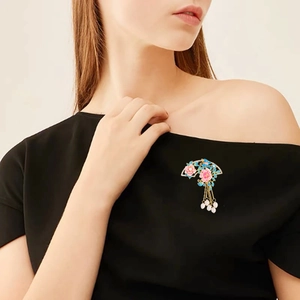 Traditional folding fan brooch with pink flowers and golden tassels on a black dress