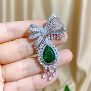 Elegant silver bow brooch with emerald water drop gemstone and sparkling tassels