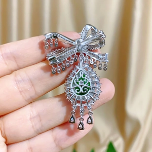 Detail of silver bow brooch back with water drop green gemstone and tassel accents