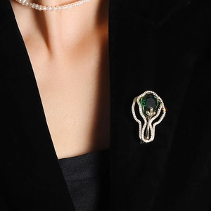 Broche vintage avec pierre verte et cristaux blancs sur un revers de blazer noir