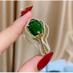 Détail d'une broche de style palais vintage avec pierre verte poire et cristaux dorés