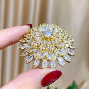 Macro shot of gold sunburst flower brooch featuring multi-layered crystal petals