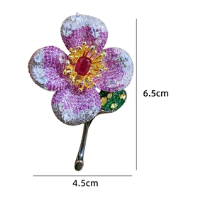 Detail of luxury flower brooch with pink petals, zircons and red center stone