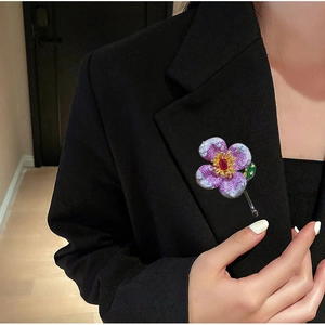 Luxurious flower brooch with red zircon on a black blazer, elegant fashion accessory