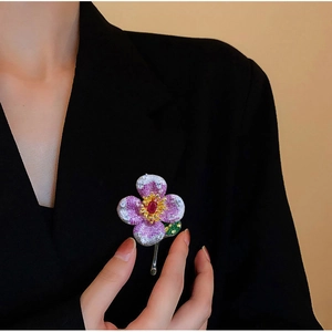 Luxurious flower brooch with purple zircon petals and red center on a black blazer