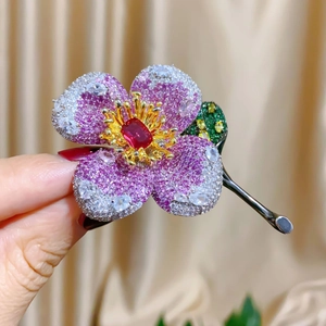 Detailed close-up of a luxury floral brooch with purple gemstones and gunmetal finish