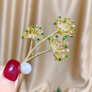 Handheld photo of a luxury golden dandelion bouquet brooch with zircons and pearl