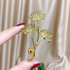 Macro detail of a dandelion bouquet brooch with green zircon and white pearl on satin
