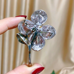 Detailed back view of the floral brooch showing the pin mechanism and hollow metalwork