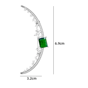 Detailed view of crescent moon brooch with dimensions 6.9cm by 3.2cm and emerald gemstone