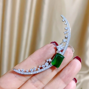 Elegant crescent moon brooch with green gemstone and micro-paved zircons held in hand