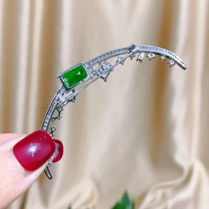 Macro detail of silver moon brooch with zircon pave and rectangular emerald gemstone