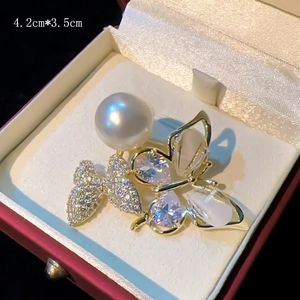 Golden butterfly brooch with white pearl and crystal wings in a red jewelry gift box