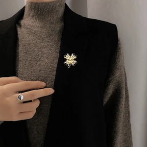 Detail of a gold four-leaf clover brooch with sparkling zircons on a black blazer lapel