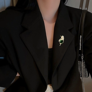Broche vintage dorée avec pierre précieuse verte ovale sur un revers de blazer