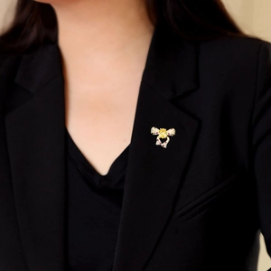 Détail d'une broche élégante en forme de nœud avec cristaux jaunes et rouges sur un blazer