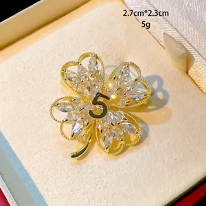 Macro shot of gold four-leaf flower brooch with zircons and number 5, size 2.7x2.3cm