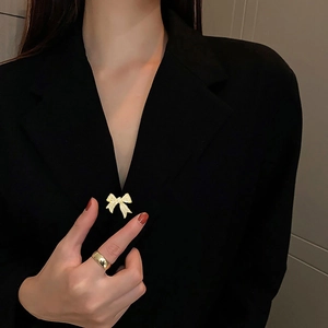 Nahaufnahme einer goldenen Schleifenbrosche mit Zirkonia und einem polierten Ring