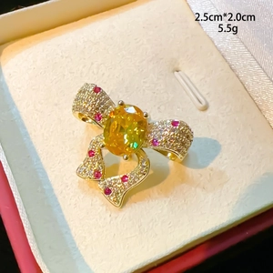 Détail d'une broche nœud dorée avec pierre ovale jaune et pavé de cristaux brillants