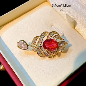 Elegant gold maple leaf brooch with ruby and zircon accents in a premium jewelry box