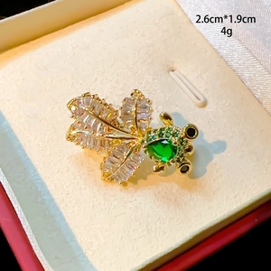 Nahaufnahme einer goldenen Goldfischbrosche mit lila Zirkon und grünen Wassertropfensteinen