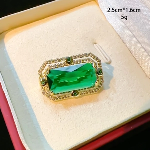 Détail macro de la broche émeraude verte avec cadre doré, taille 2,5 cm par 1,6 cm