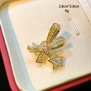 Detailed size view of a 2.8cm golden bow brooch with zircons in a luxury red gift box