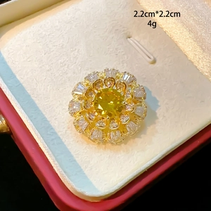 Macro detail of a 2.2cm flower brooch with yellow zircon and gold base in red box