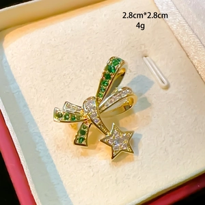 Detailed close-up of emerald green bow brooch with hanging star charm and size marking
