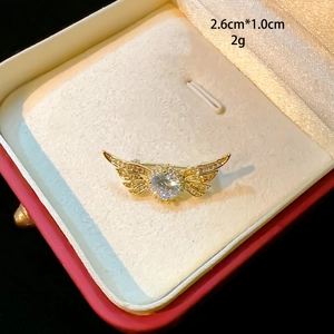 Gros plan broche aile dorée avec zircon, 2,6cm x 1,0cm, sur boîte cadeau en velours