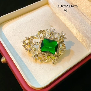 Eleganter goldener Kronen-Brosche mit smaragdgrünem Kristall und funkelnden Straßsteinen