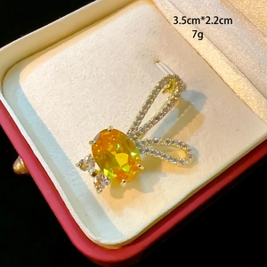 Détail d'une broche oreilles de lapin avec pierre jaune et zircons dans un écrin