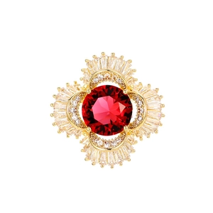 Elegant gold clover brooch with a large red gemstone and sparkling diamond accents