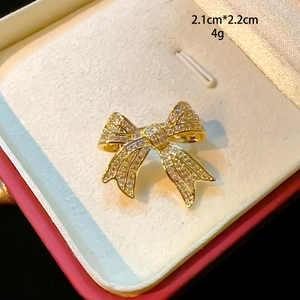 Gros plan sur une broche nœud dorée avec cristaux affichant les mesures 2,1cm x 2,2cm
