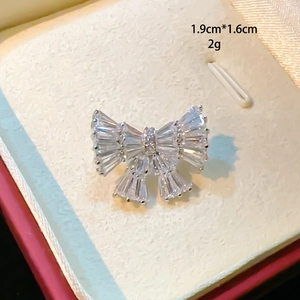 Makroaufnahme einer silbernen Schleifenbrosche mit Zirkonia-Steinen, Größe 1,9 x 1,6 cm