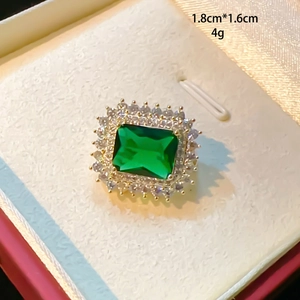 Makroaufnahme eines grünen Rings mit Smaragdschliff und Goldfassung im Schmuckkästchen