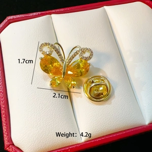 Detail shot of a luxury butterfly brooch with yellow gemstones and size specifications