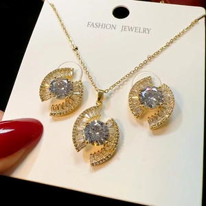 Detailed close-up of a gold-plated evil eye necklace and stud earrings set with zircons