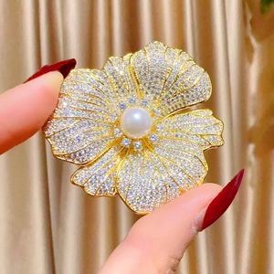 Vue détaillée d'une broche fleur dorée sertie de zircons avec perle d'eau douce